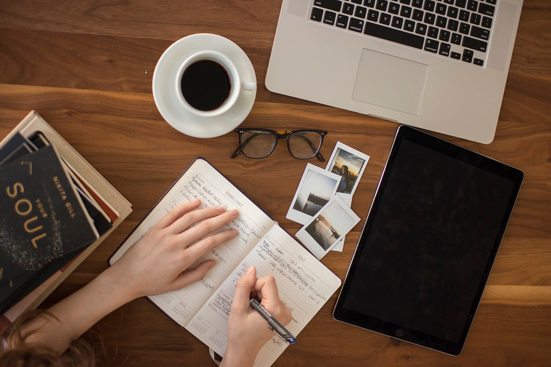 Pessoa a planear os seus objetivos ao lado do computador, com café